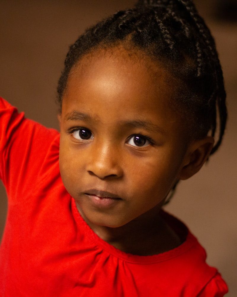 Kinderfrisur mit Cornrows, Kind im roten Oberteil